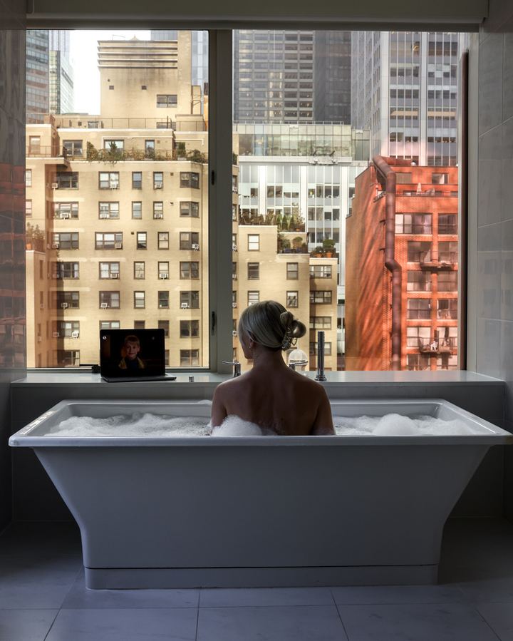 Soaking tub facing a window with a view of midtown Manhattan