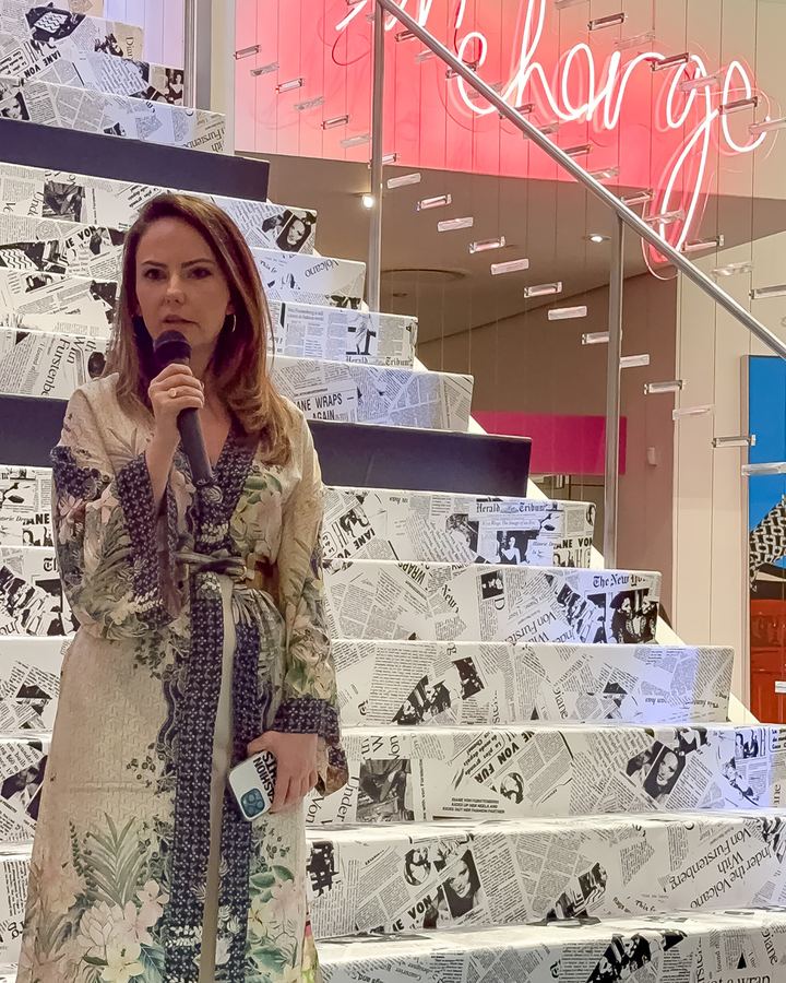 Didi Vukatana speaking into a microphone at a Fashion Fights Cancer event